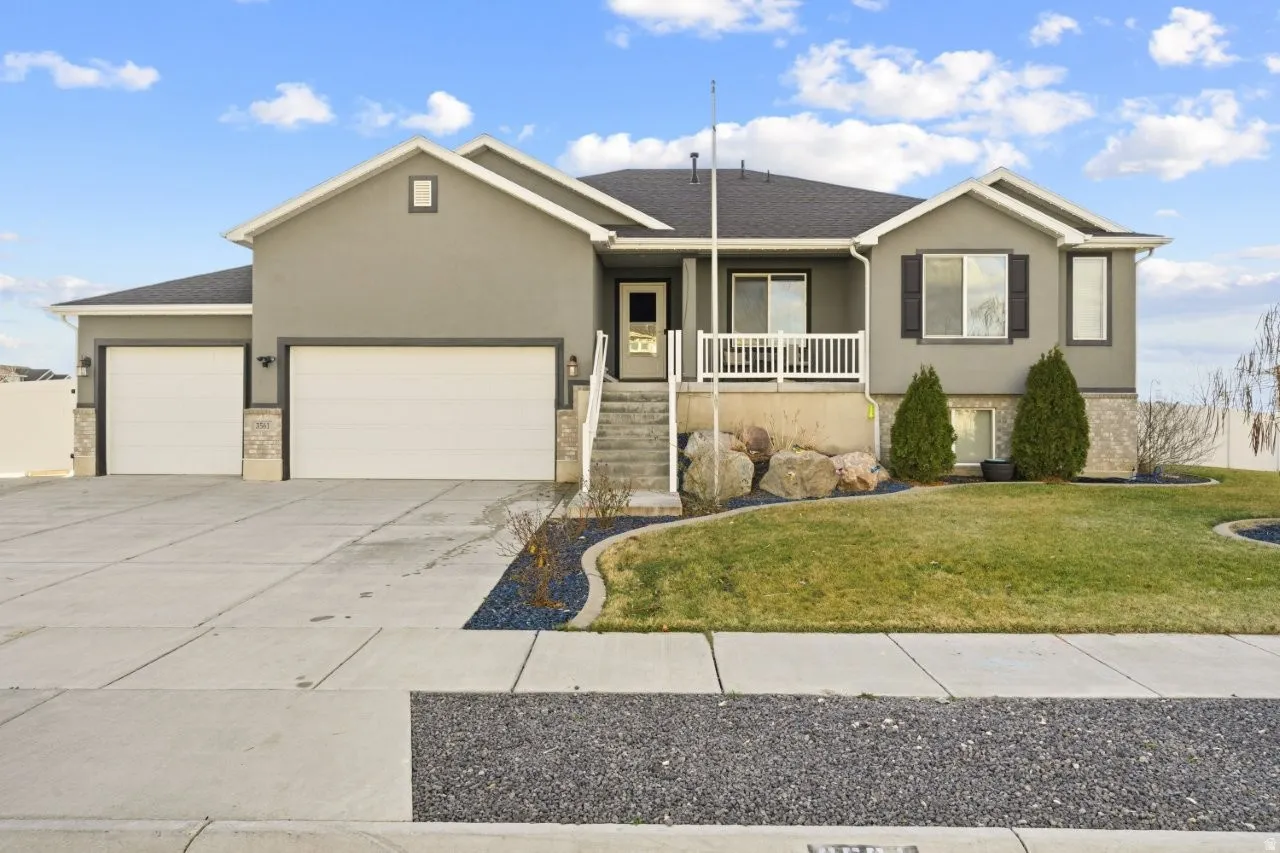 Single story home with an attached garage, stucco siding, driveway, a porch, and a front lawn