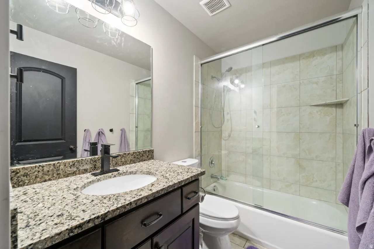 Bathroom featuring a dark wood-finish vanity with an undermount sink, granite countertop, and matte black faucet