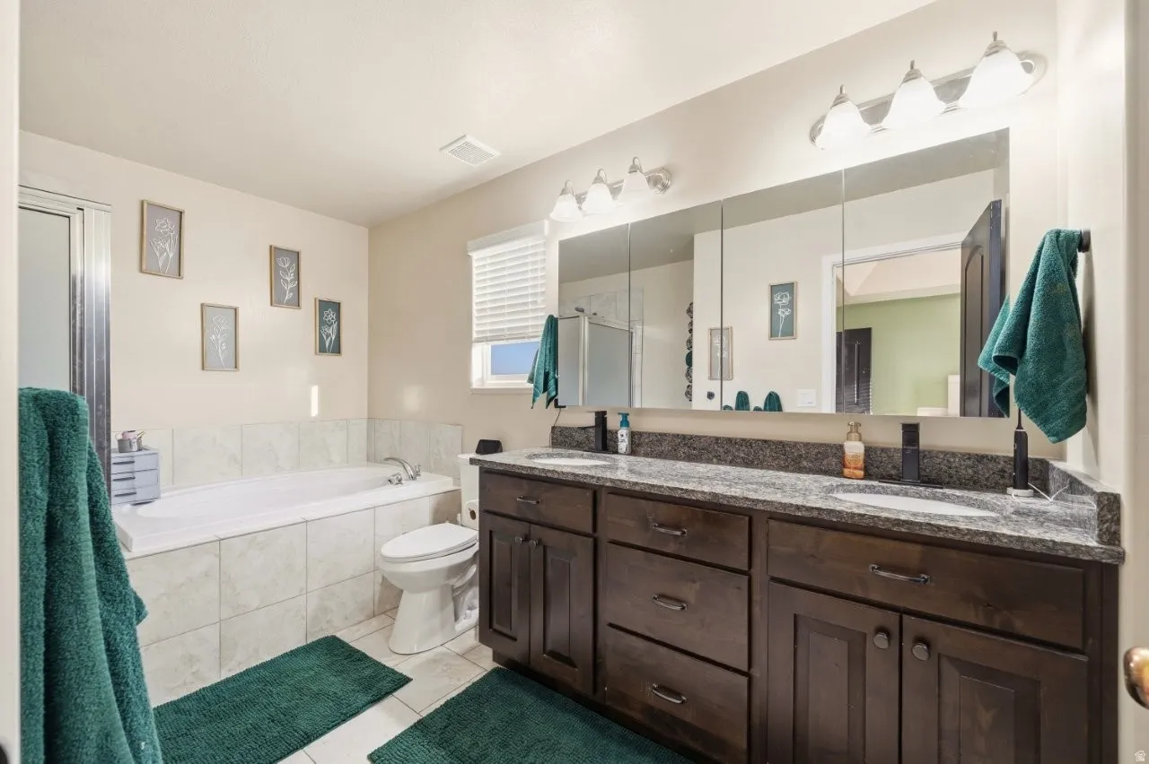 Bathroom featuring double vanity, a stall shower, a bath, and light tile patterned floors