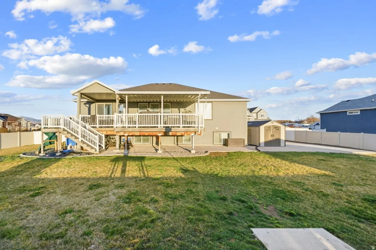 Back of house with a storage unit, a patio area, a deck, and stucco siding