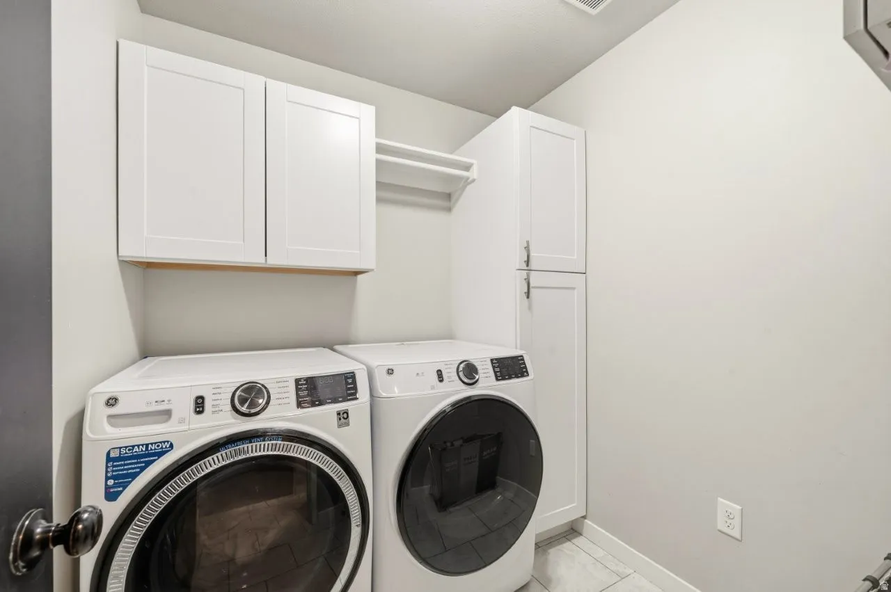 Laundry room with cabinet space, washer and clothes dryer, and light tile patterned floors