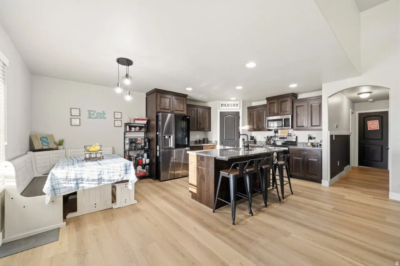 Kitchen with stainless steel appliances, dark wood finish cabinetry, a breakfast bar area, an island with sink, and arched walkways