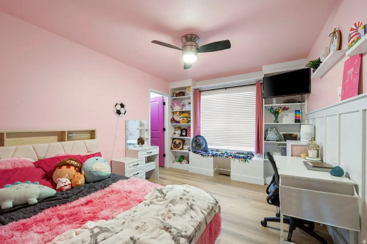 Bedroom featuring an office area, light wood-style floors, and a ceiling fan