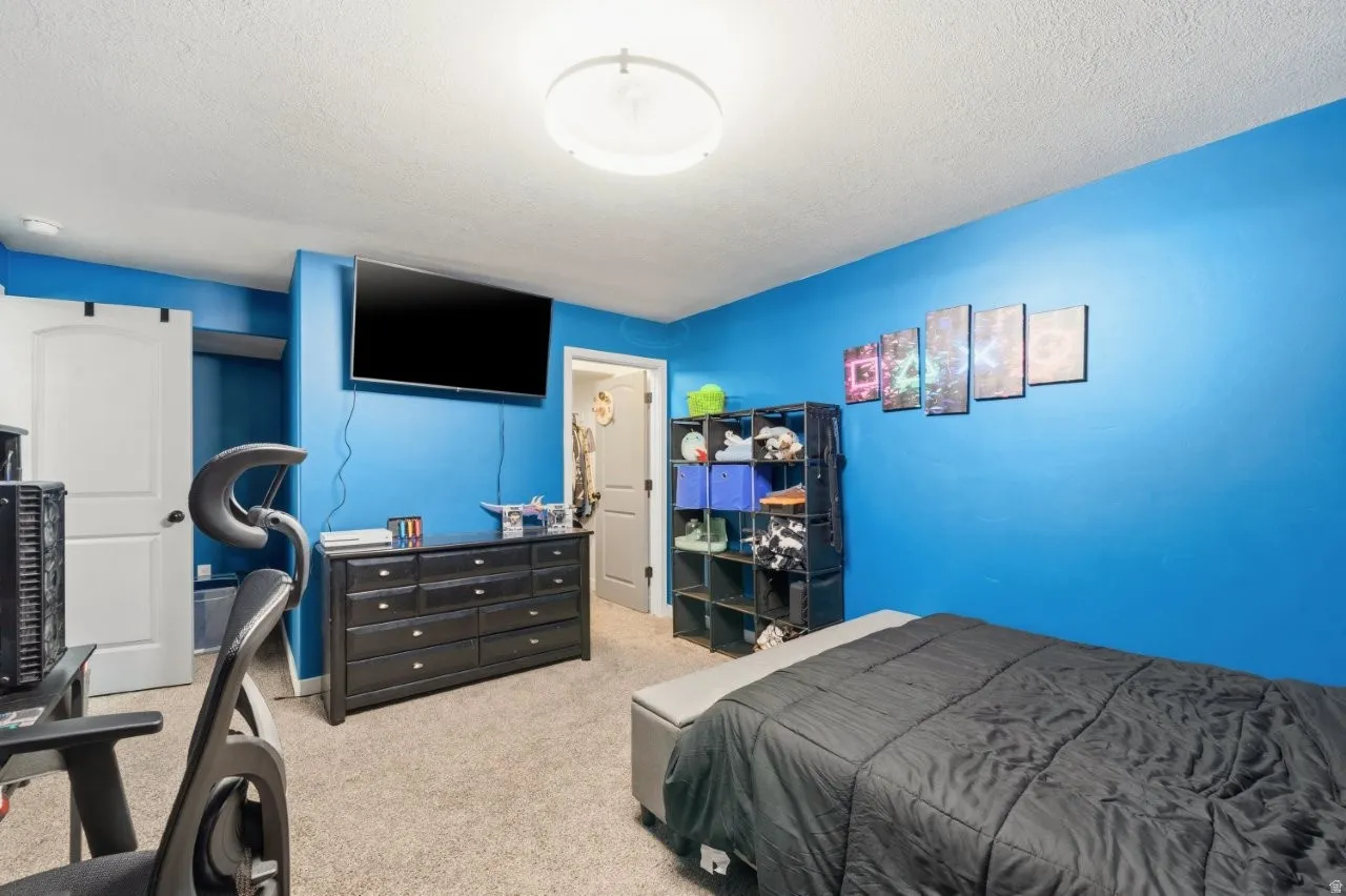 Bedroom featuring light colored carpet and a textured ceiling