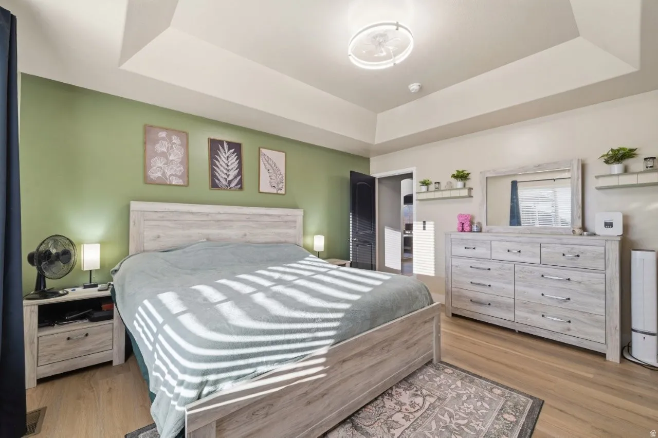 Bedroom featuring light wood-style floors and a raised ceiling
