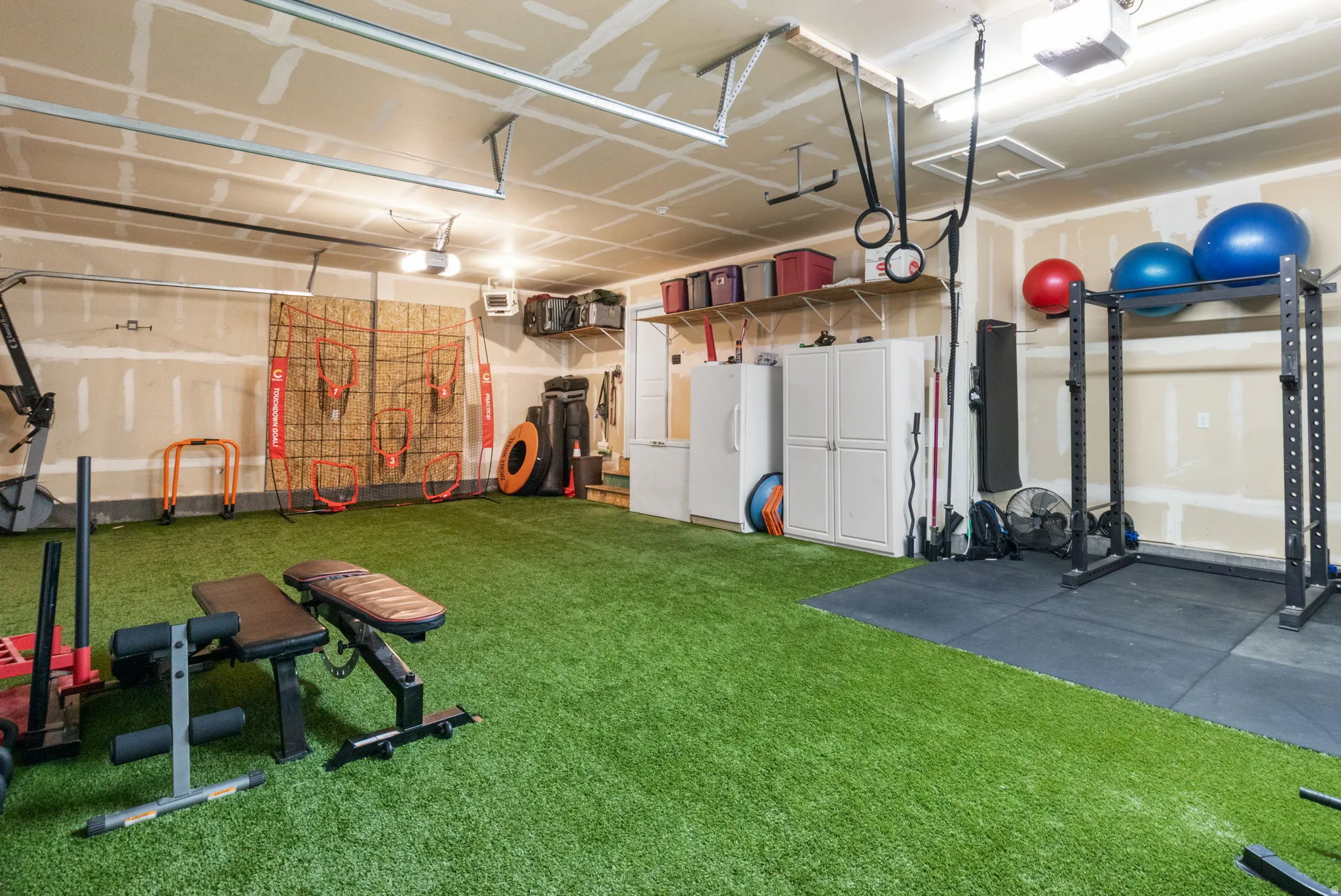 Garage with freestanding refrigerator, a garage door opener, and a heating unit