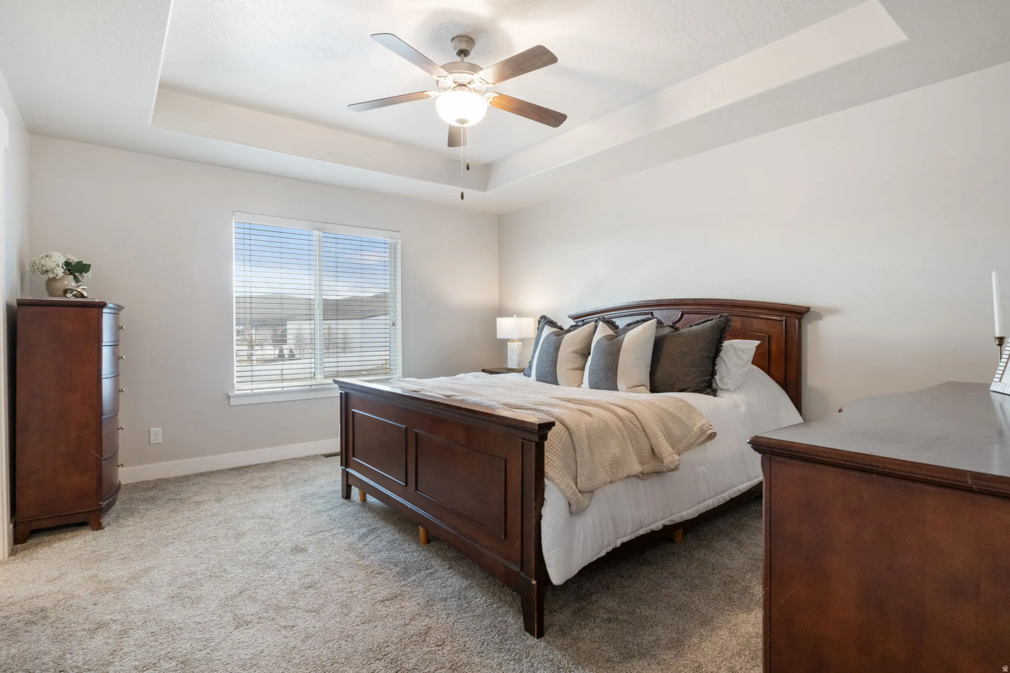 Bedroom with a tray ceiling, carpet, and a ceiling fan
