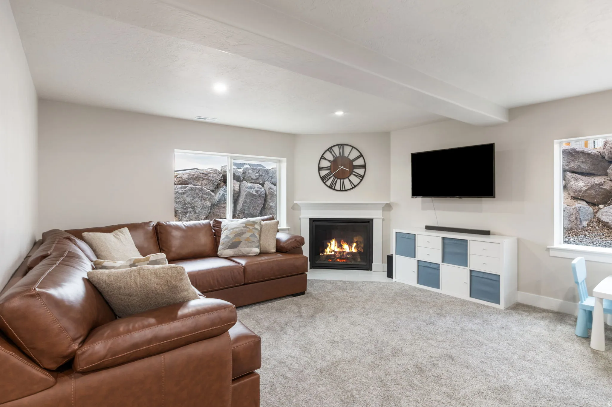Living area featuring a glass covered fireplace, light carpet, beamed ceiling, and recessed lighting