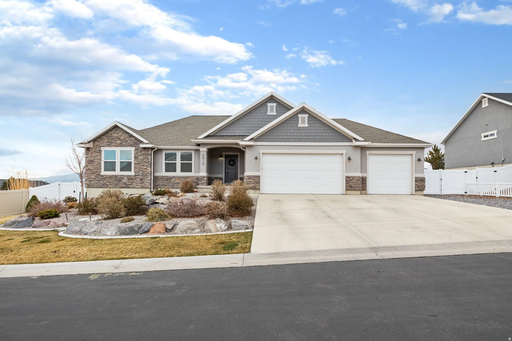 Craftsman-style house with a garage, stone siding, a gate, and driveway