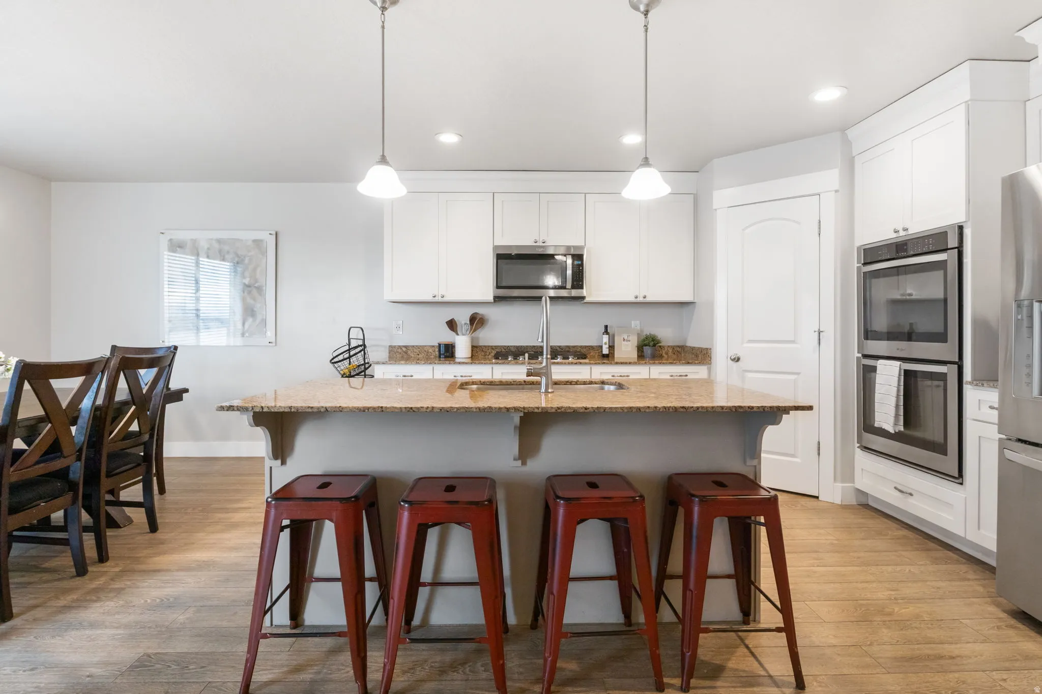 Kitchen featuring a breakfast bar, light stone counters, stainless steel appliances, and an island with sink