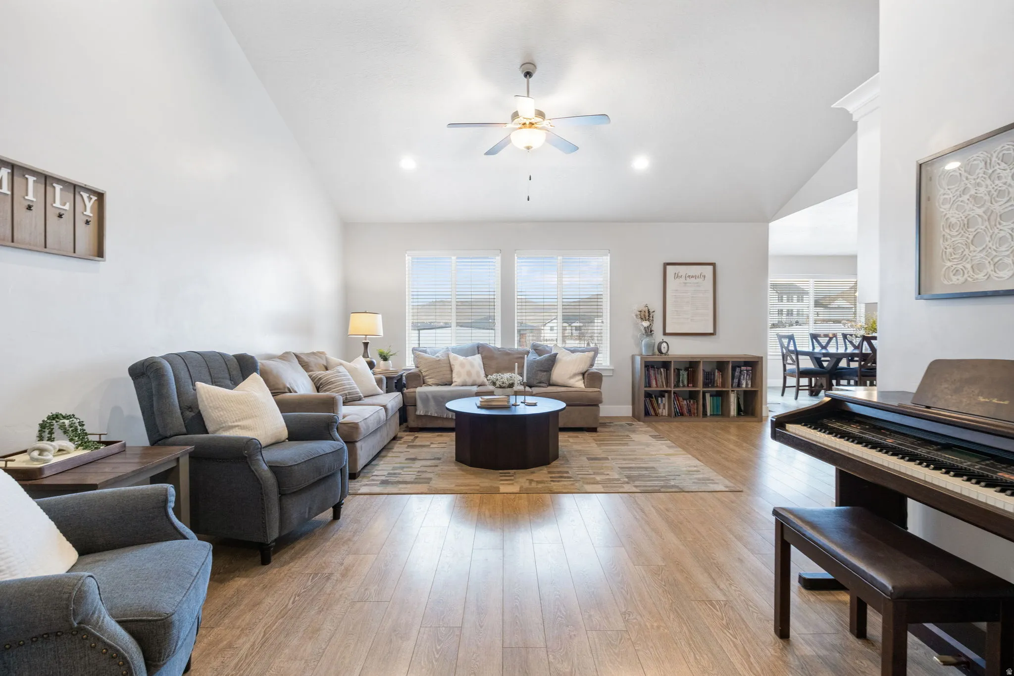 Living room with light wood-type flooring, ceiling fan, and vaulted ceiling