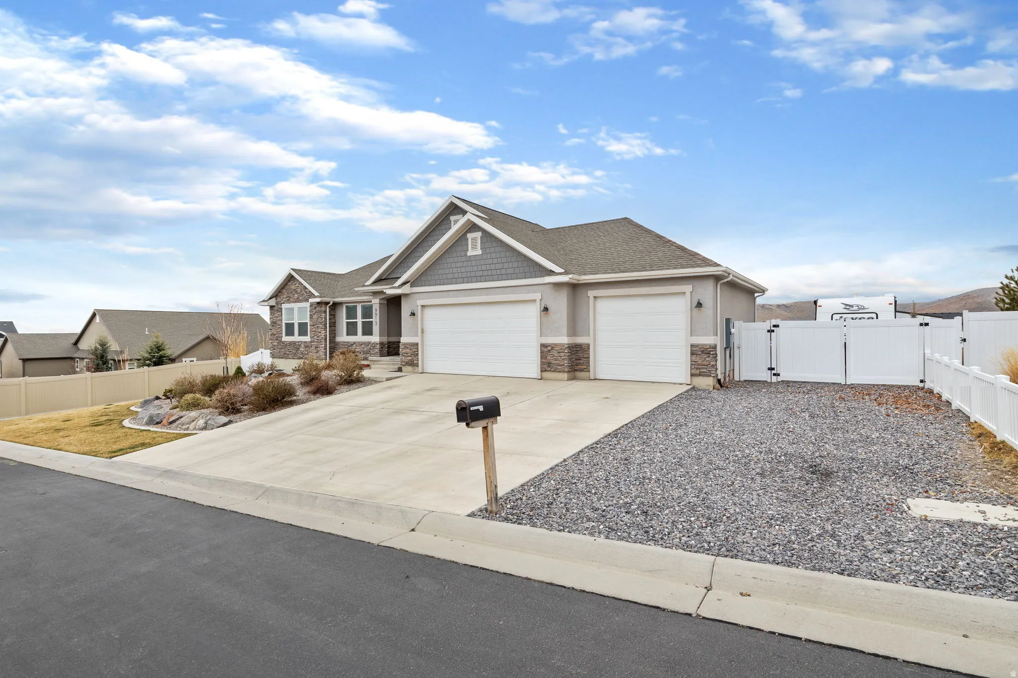 Craftsman-style house with a gate, a garage, driveway, and stone siding