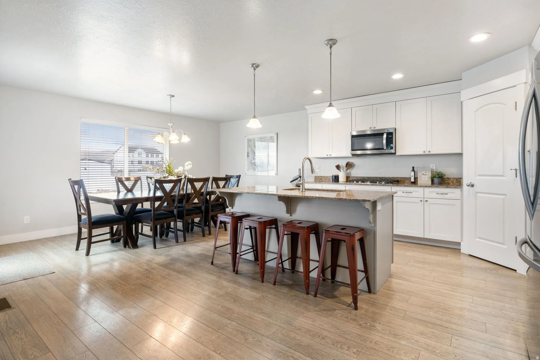 Kitchen with a breakfast bar area, a center island with sink, dark stone counters, stainless steel appliances, and light wood-style floors
