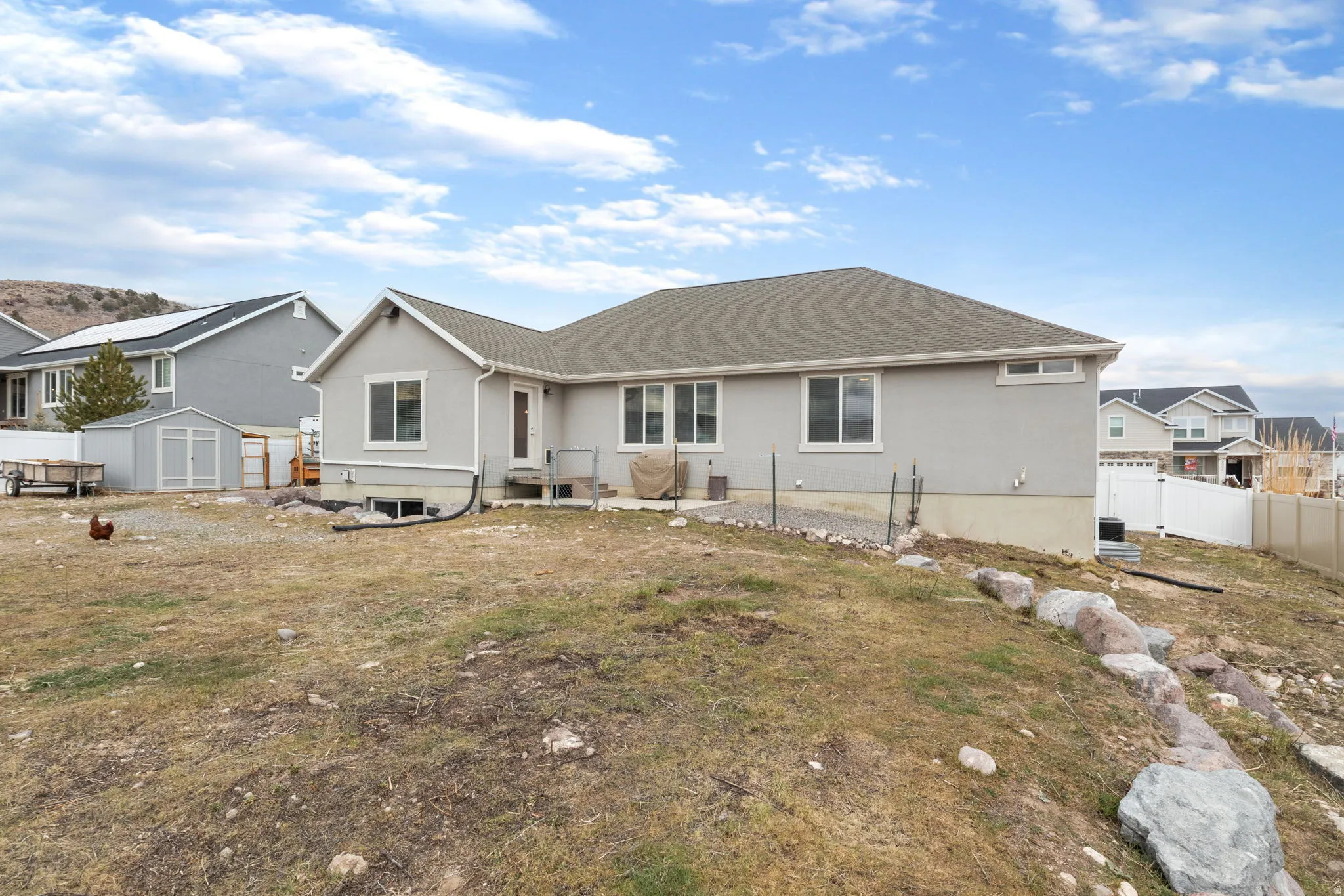 Rear view of property featuring a shed, stucco siding, and roof with shingles