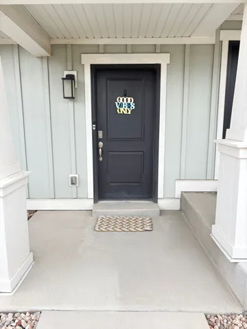 View of exterior entry with covered porch and board and batten siding