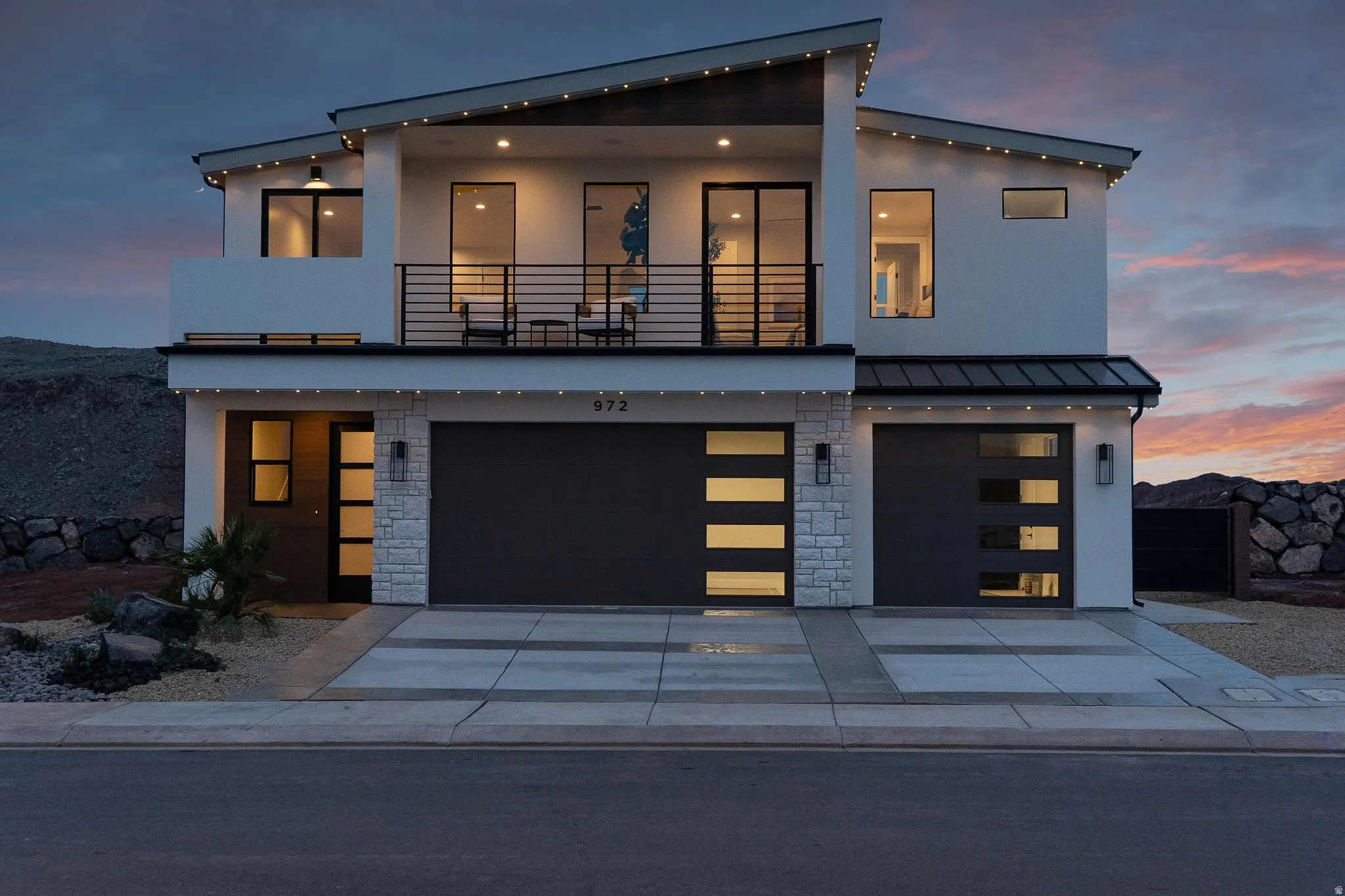 Contemporary house with stone siding, a balcony, and stucco siding