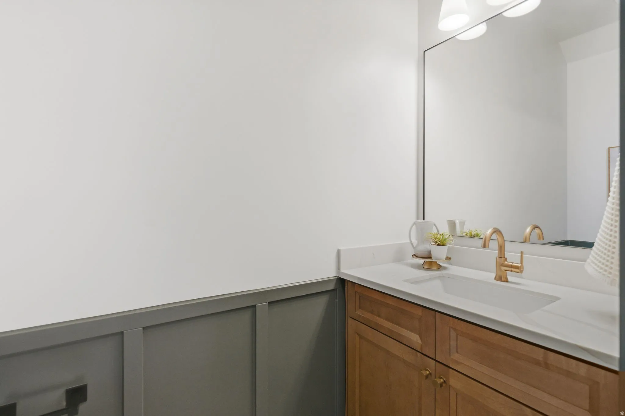 Bathroom featuring a decorative wall, a wainscoted wall, and vanity