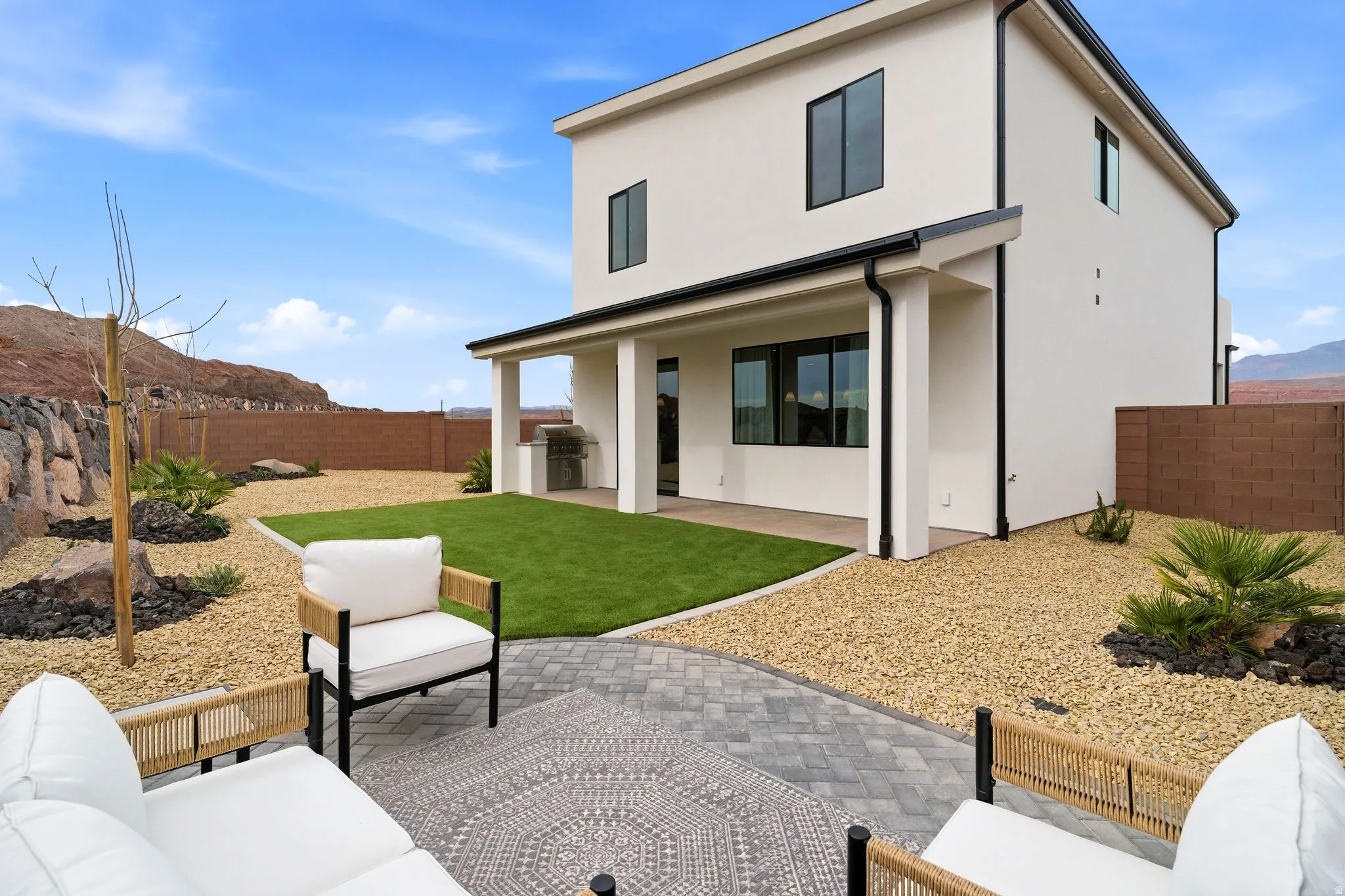 Back of house featuring a patio area, stucco siding, a mountain view, a fenced backyard, and an outdoor kitchen with living area