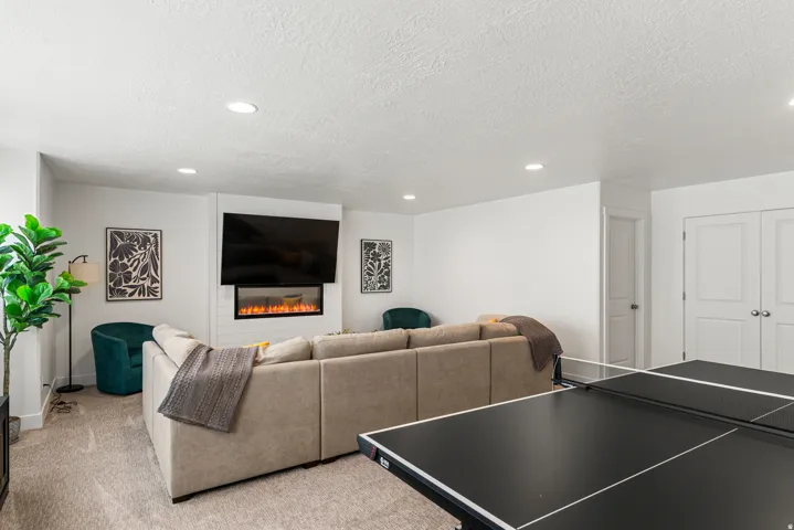 Spacious room featuring recessed lighting, a built-in electric fireplace, and light-toned carpeting