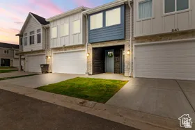 View of front of property with board and batten siding, a garage, driveway, and stone siding