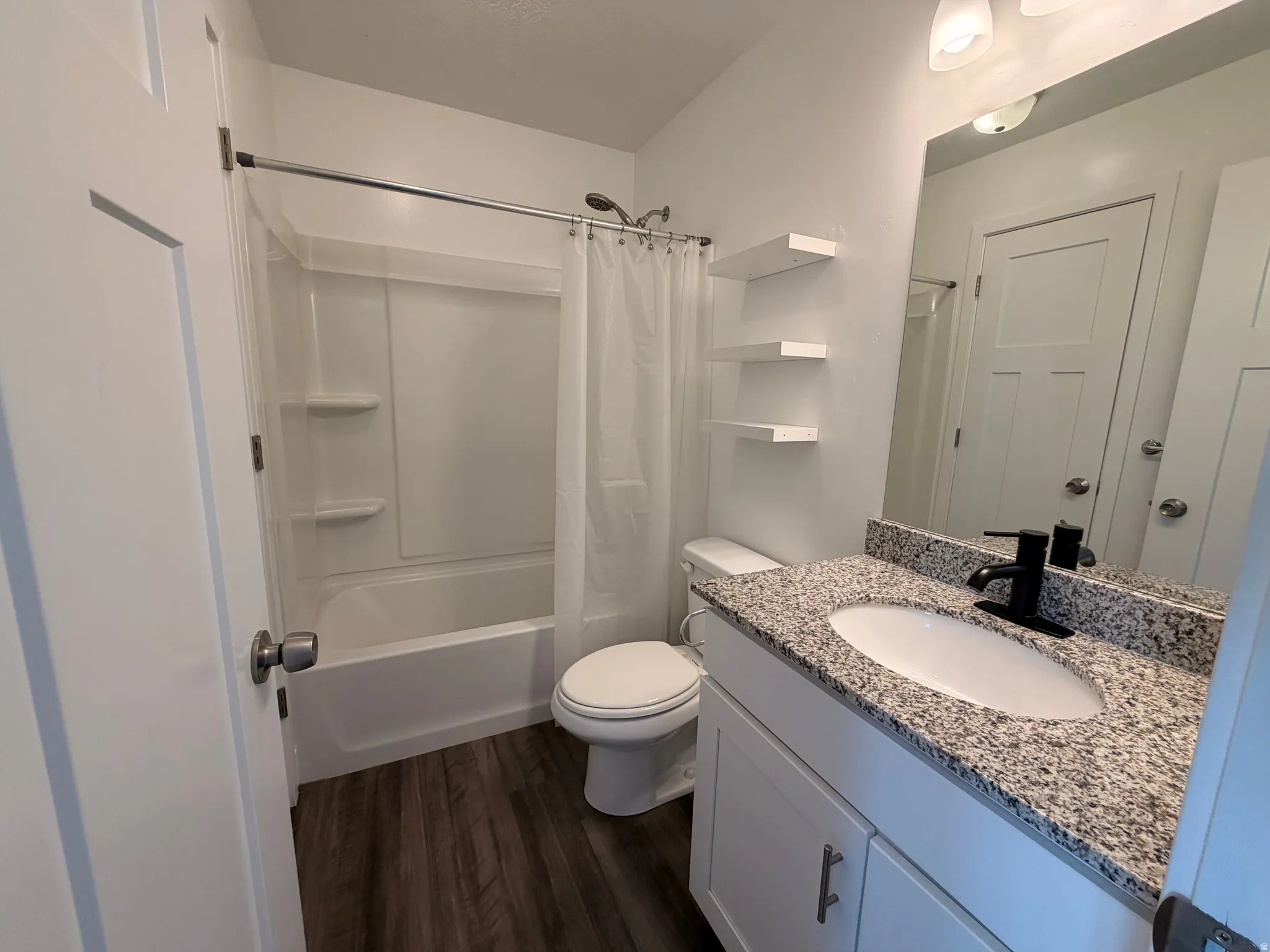 Bathroom featuring vanity, dark wood-style floors, and shower / bathtub combination with curtain