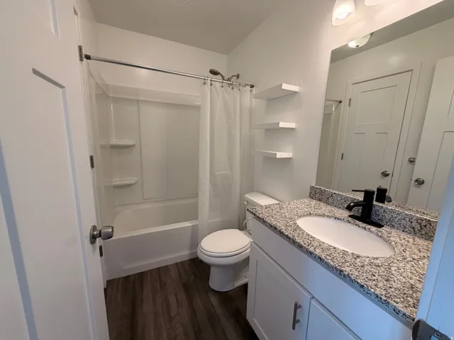 Bathroom featuring vanity, dark wood-style floors, and shower / bathtub combination with curtain
