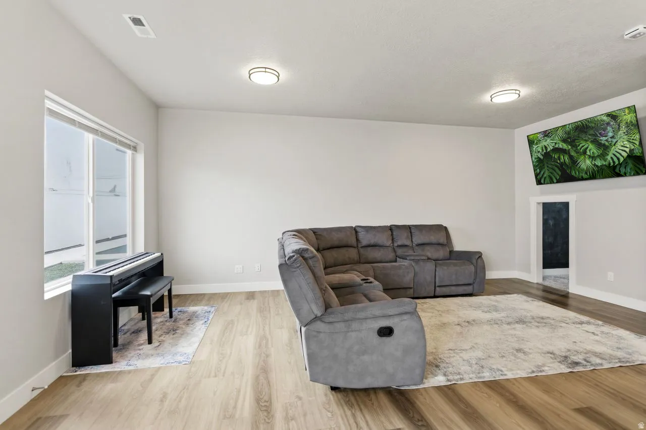 Open family room with wood-style flooring, large window and play area under the stairs