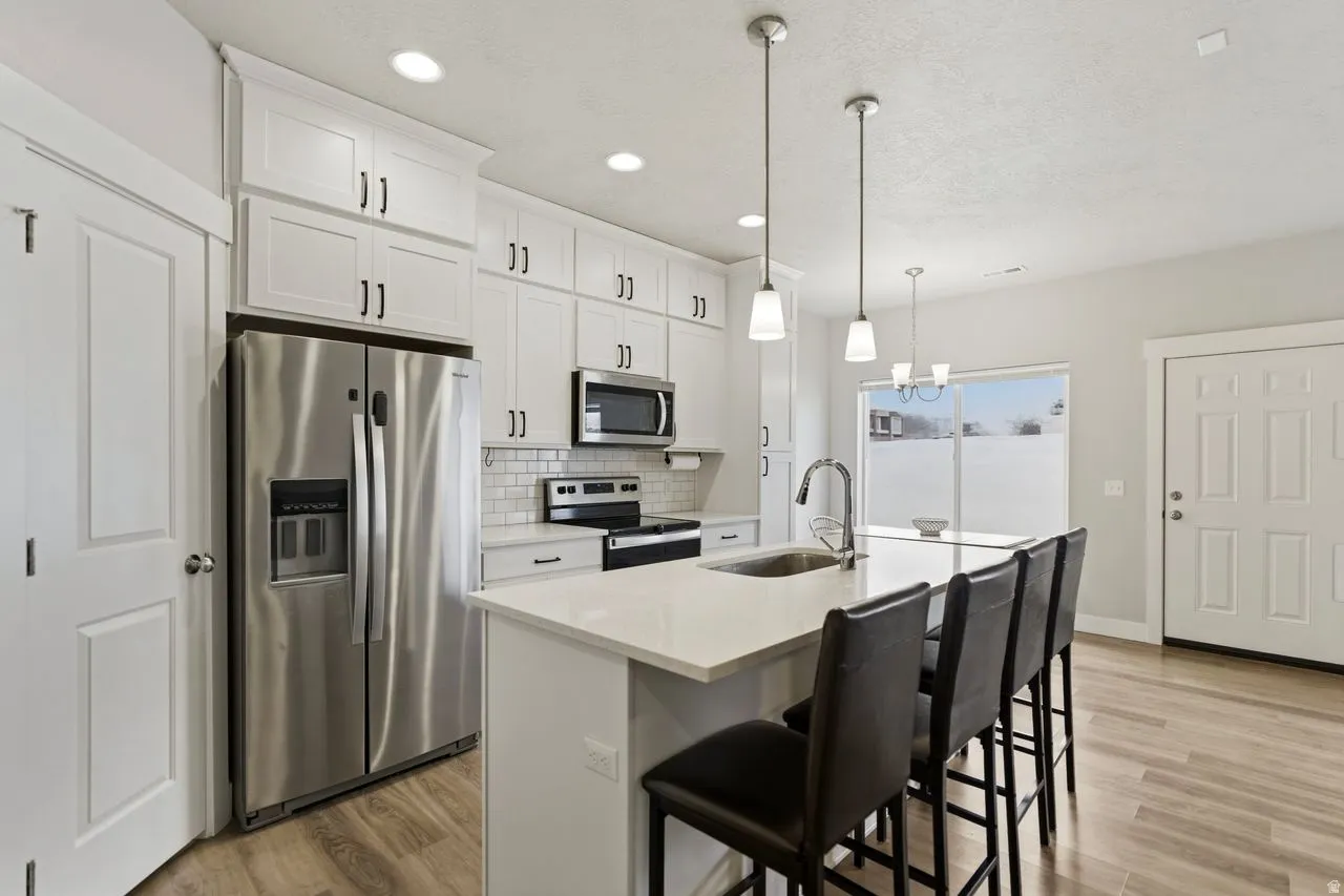 Kitchen featuring stainless steel appliances, white cabinetry, light wood-style flooring, and a textured ceiling