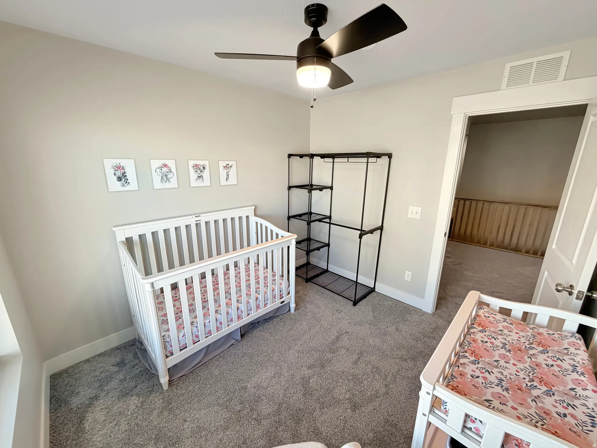 Carpeted bedroom with a crib and ceiling fan