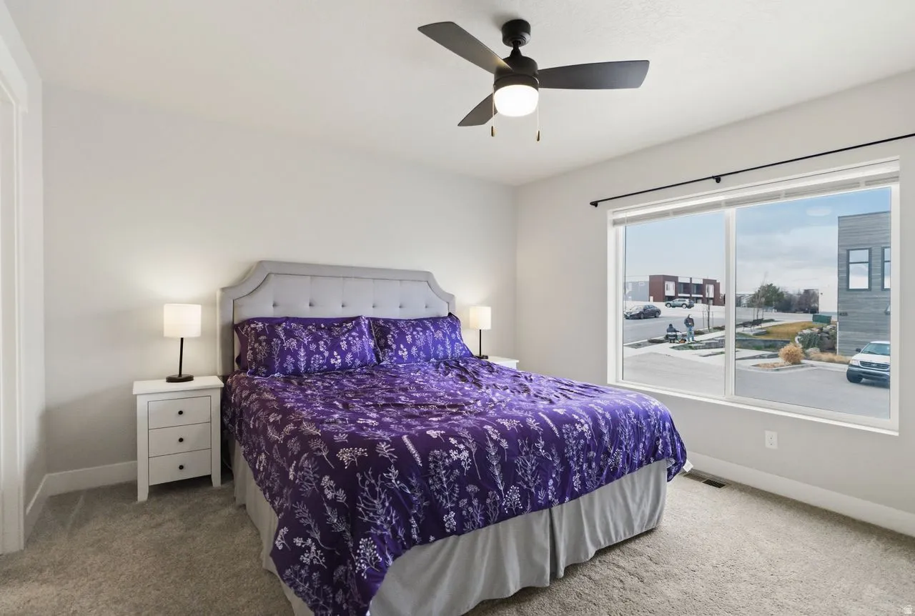 Primary bedroom with large window and ceiling fan