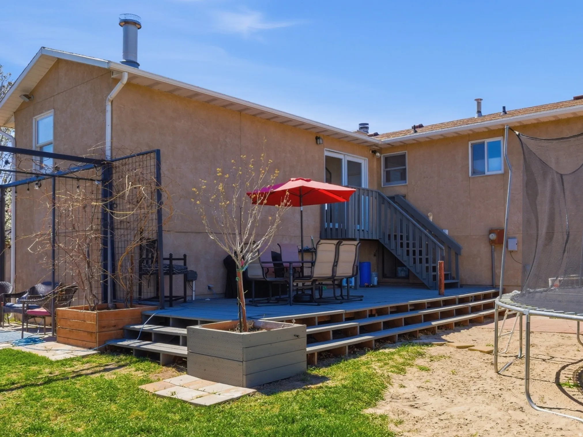 Back of property featuring a trampoline, a fenced backyard, stucco siding, and a patio area