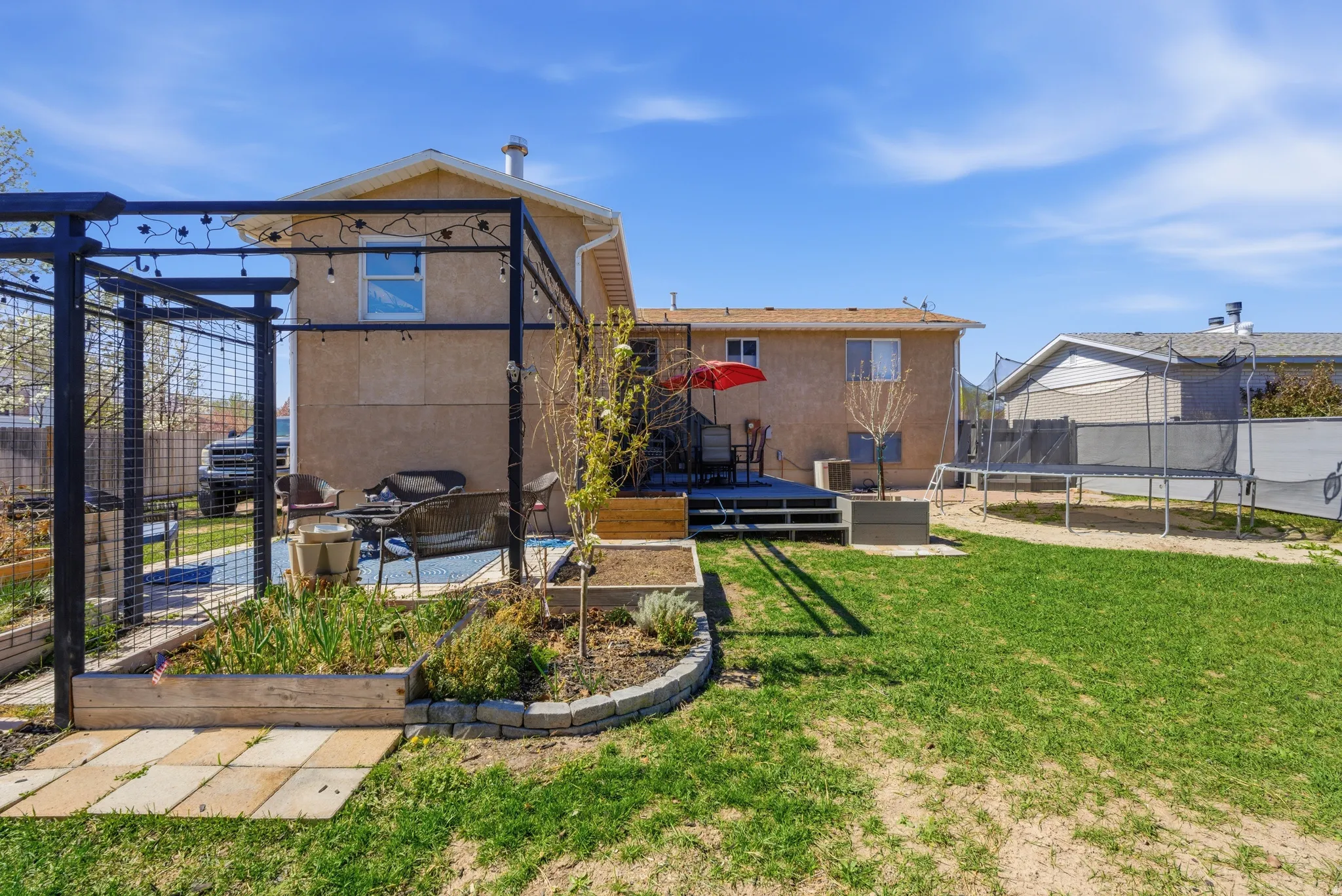 View of yard with a trampoline, a patio area, a pergola, and a wooden deck
