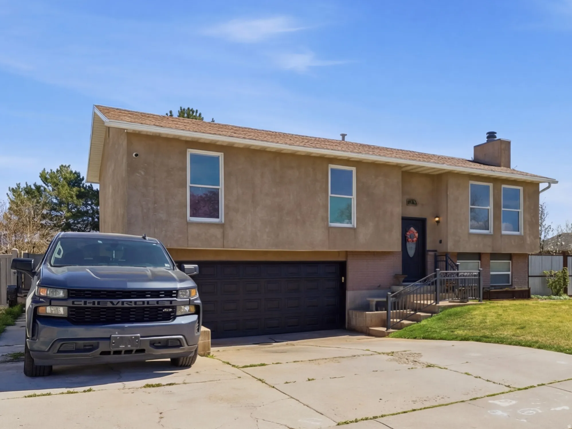 View of front of property with an attached garage, a chimney, concrete driveway, and stucco siding