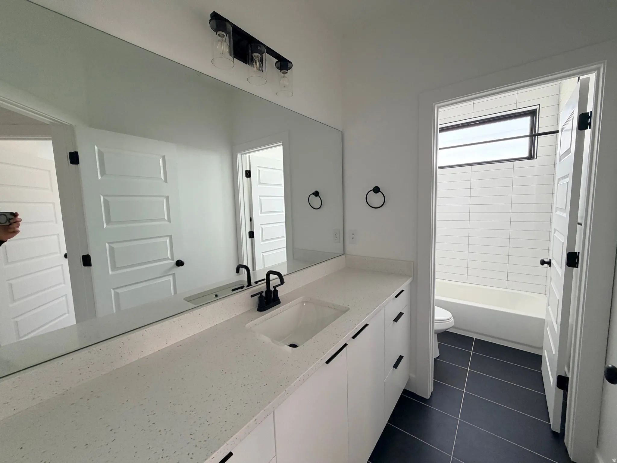 Full bath with vanity, dark tile patterned floors, and shower / bath combination