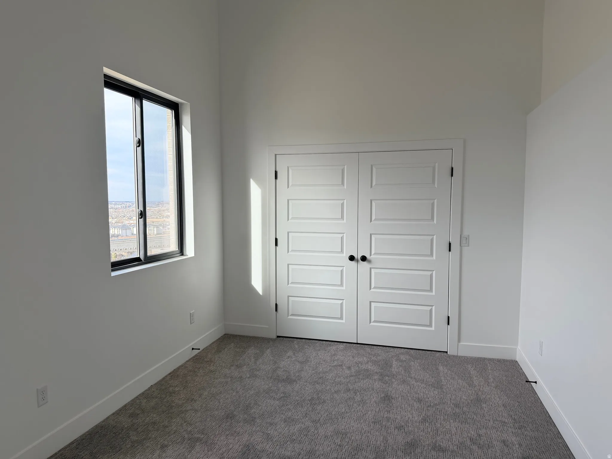 Unfurnished bedroom with dark carpet, a closet, and a high ceiling