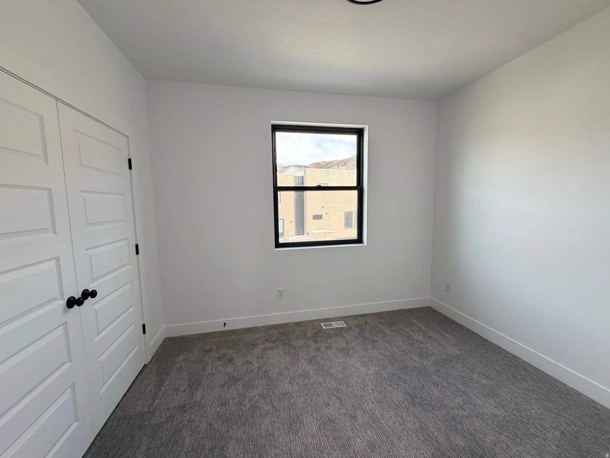 Unfurnished bedroom with a closet and dark carpet