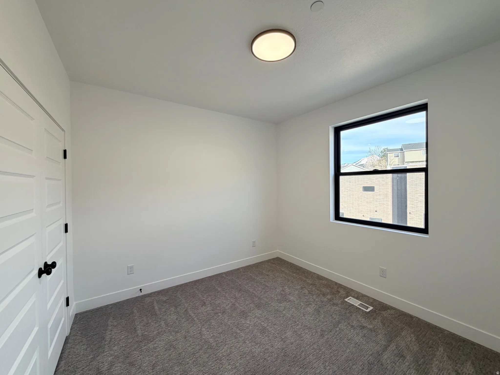 Spare room with baseboards and dark colored carpet