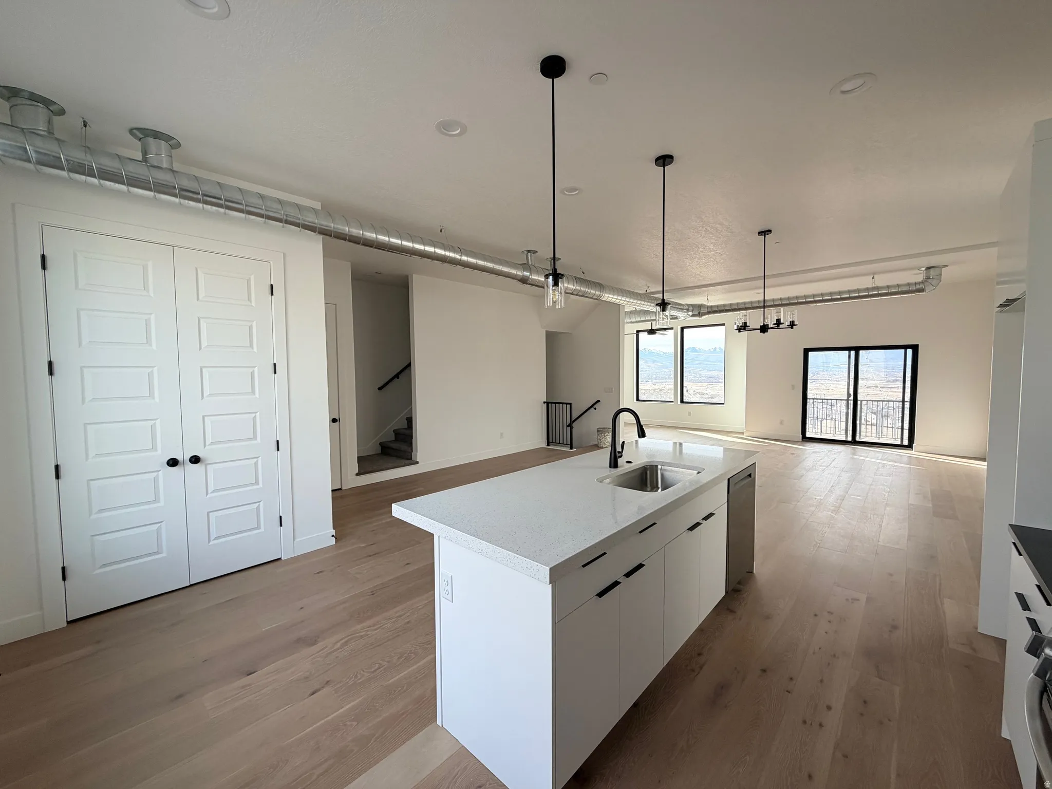 Kitchen featuring white cabinetry, open floor plan, light wood-style flooring, and a kitchen island with sink