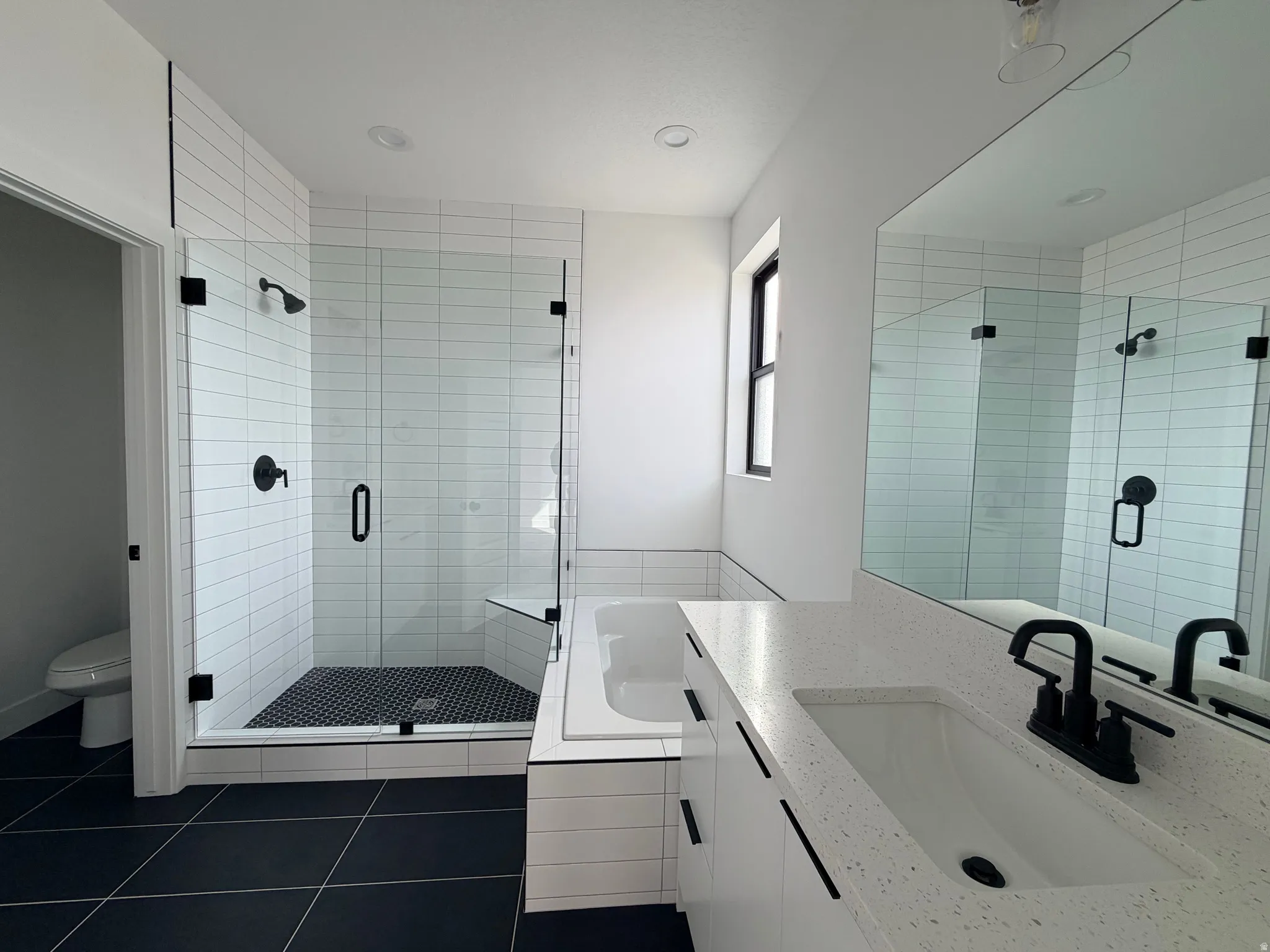 Bathroom featuring a shower stall, vanity, dark tile patterned floors, and a garden tub