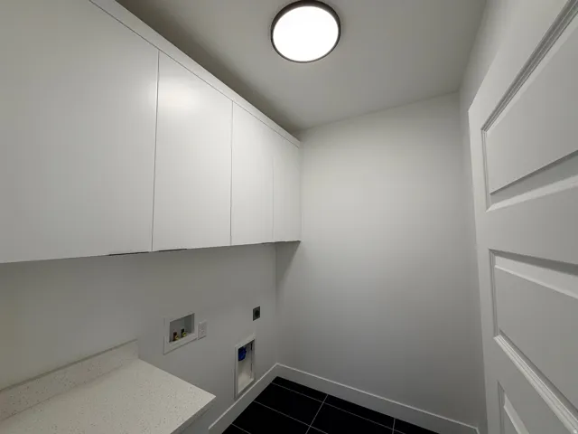 Laundry area with dark tile patterned floors, hookup for an electric dryer, cabinet space, and hookup for a washing machine