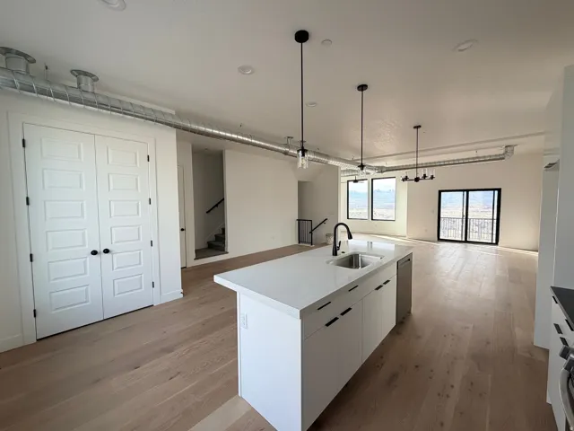 Kitchen featuring white cabinetry, open floor plan, light wood-style flooring, and a kitchen island with sink