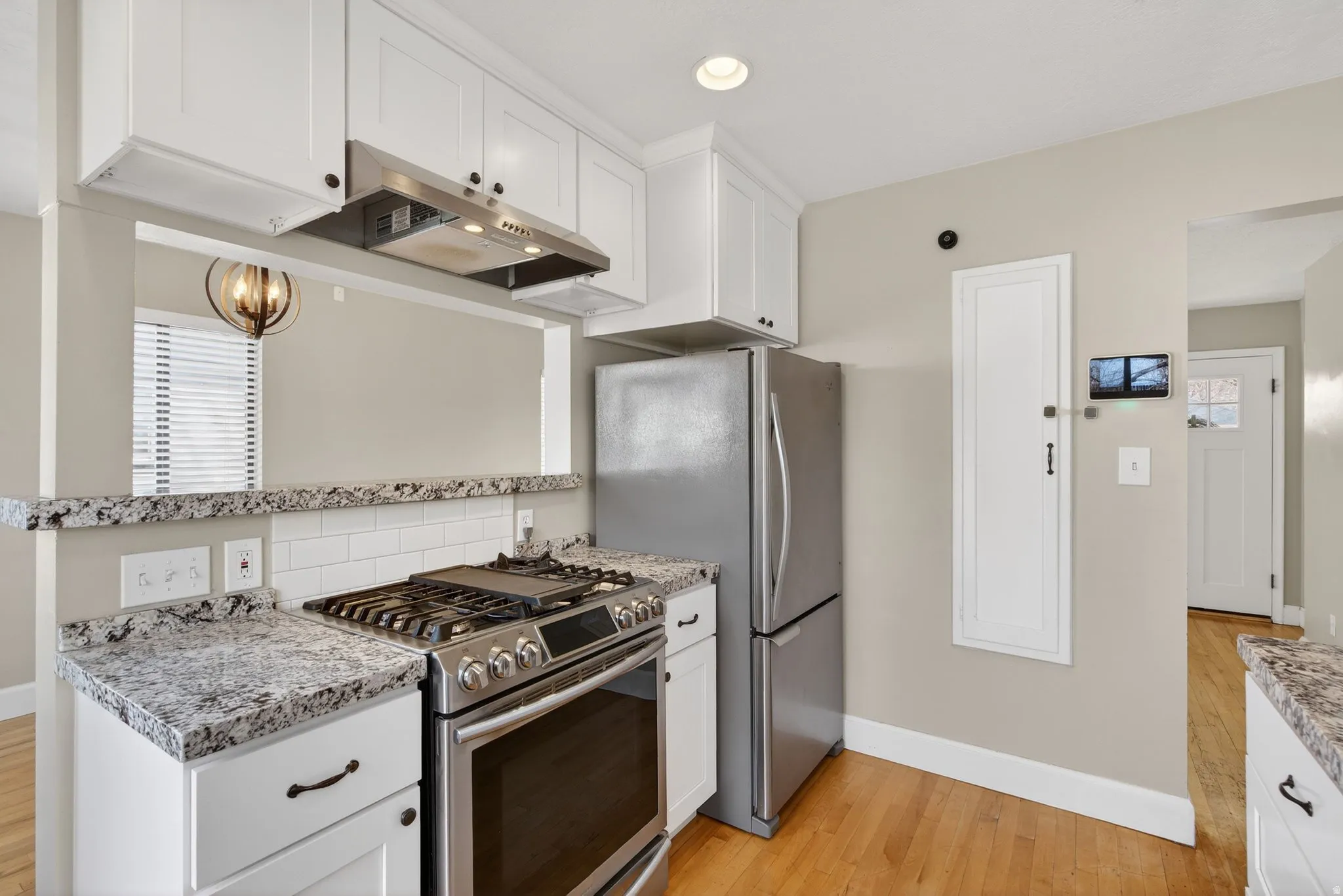 Kitchen with stainless steel appliances, white cabinets, light wood-style floors, and recessed lighting