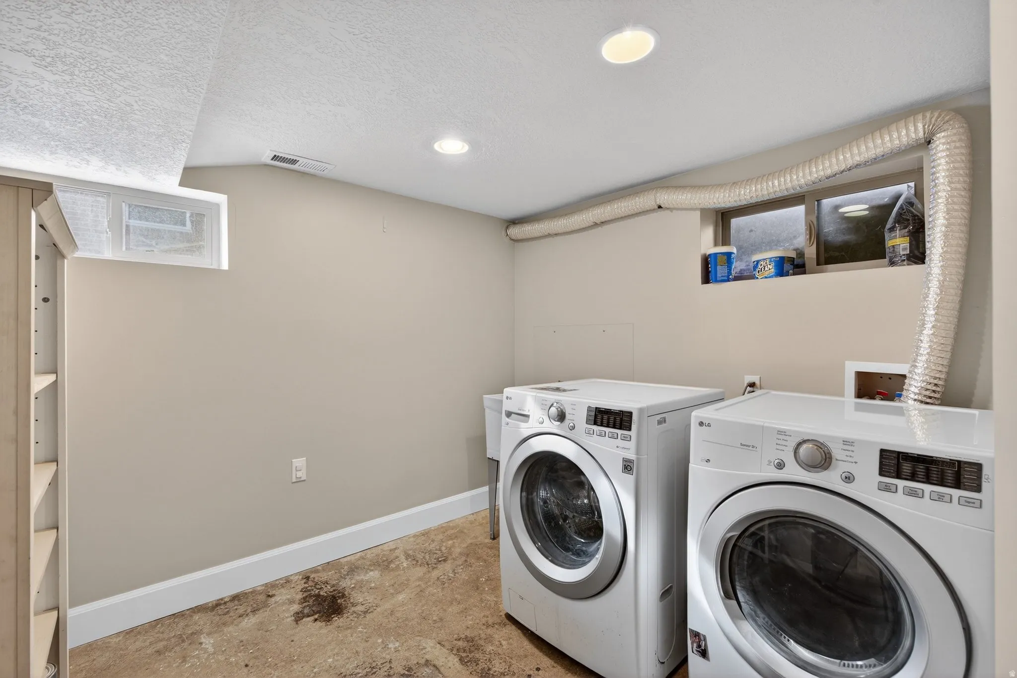 Laundry room featuring a textured ceiling, separate washer and dryer, concrete flooring, healthy amount of natural light, and recessed lighting