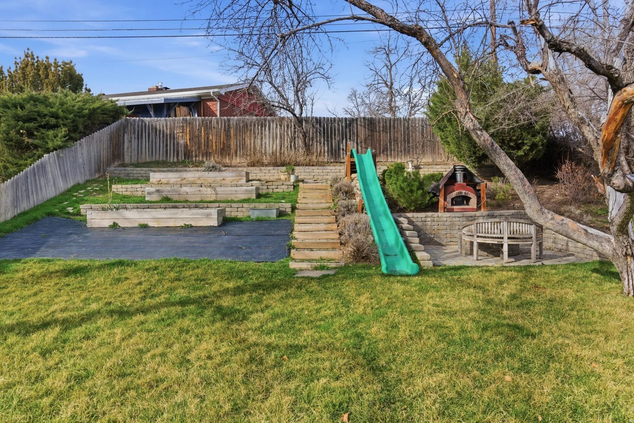 View of playground featuring a fenced backyard and a patio