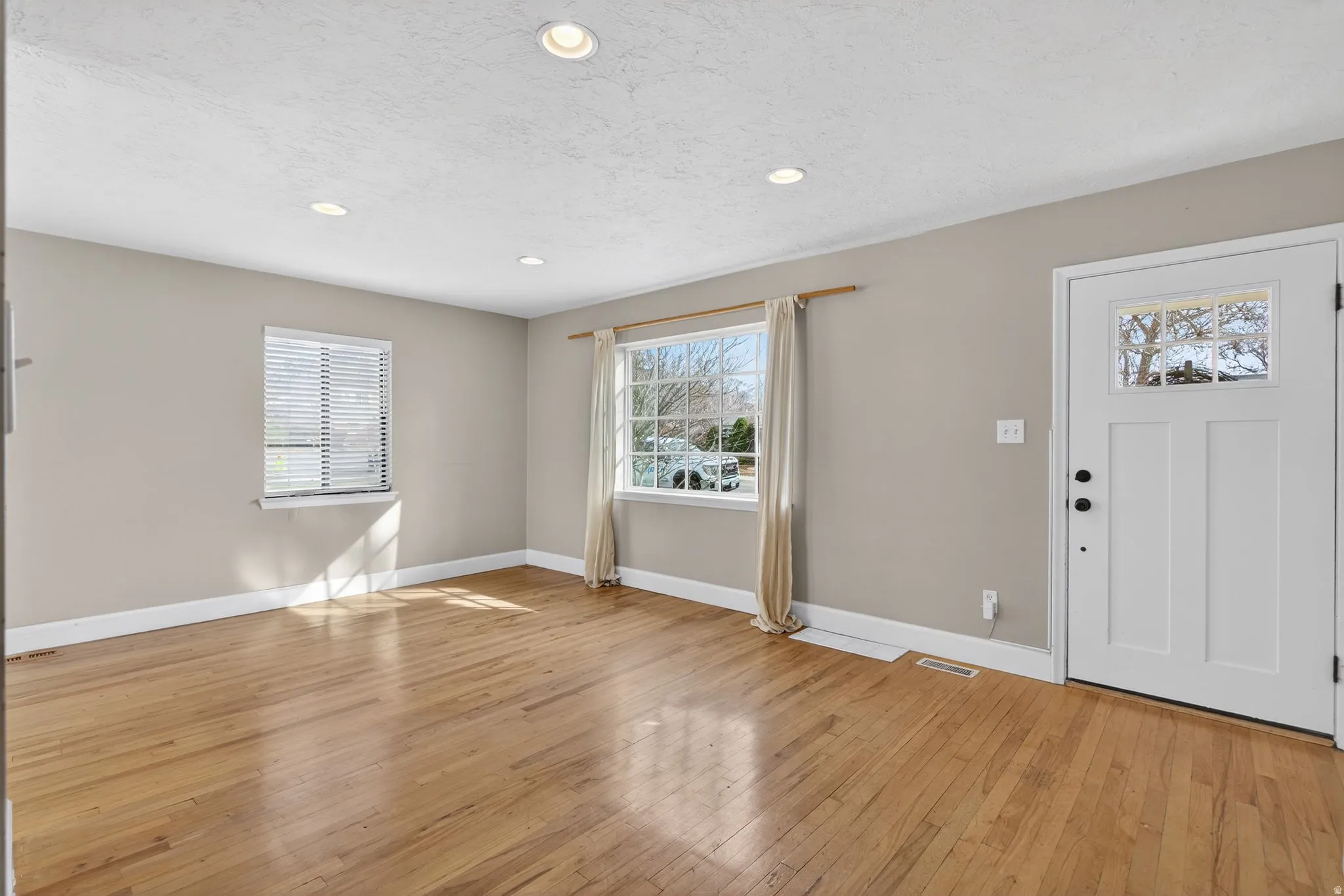 Entryway with light wood-type flooring, healthy amount of natural light, recessed lighting, and a textured ceiling