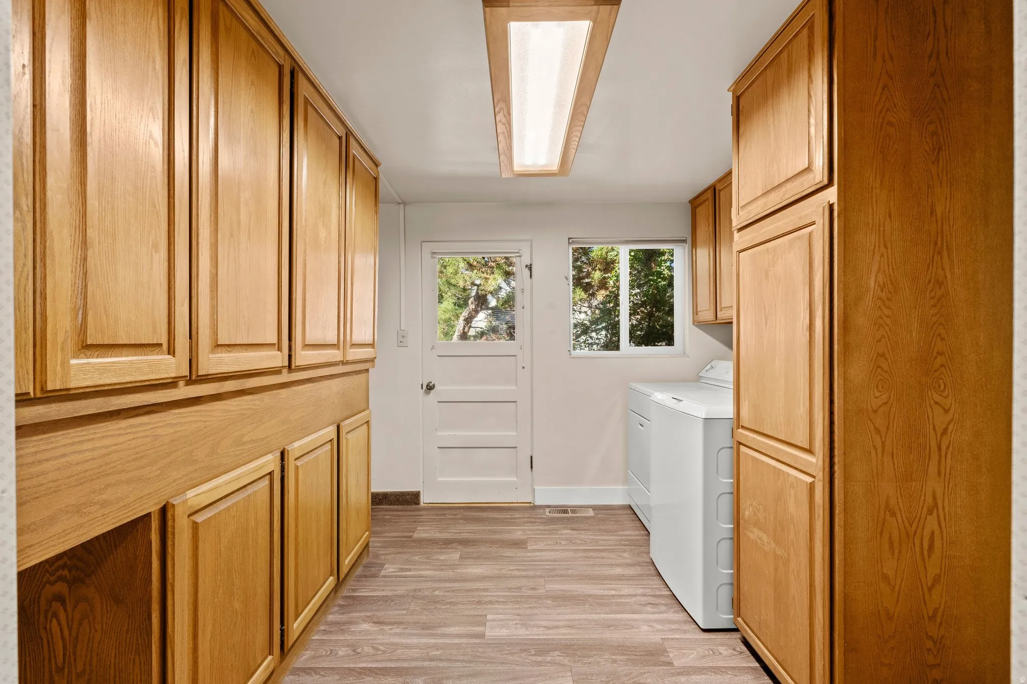 Laundry area featuring cabinet space, light wood finished floors, and washer and dryer