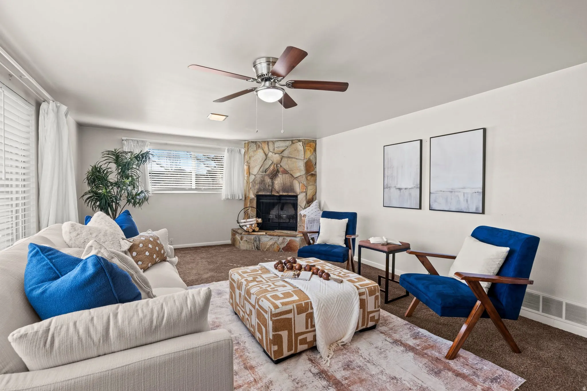 Carpeted living area with a ceiling fan and a fireplace