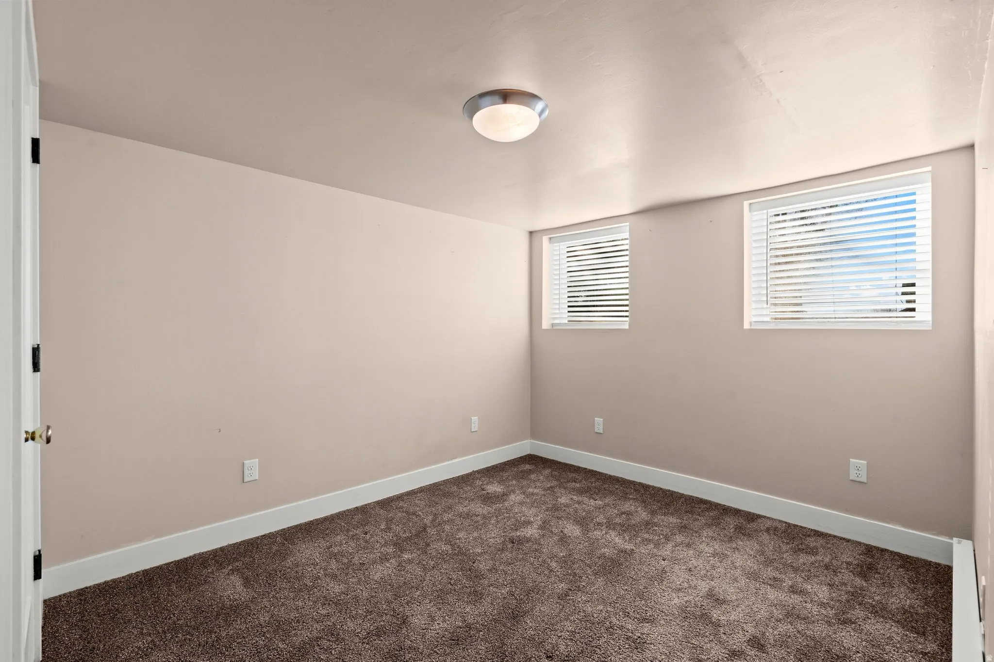 Spare room featuring dark carpet and baseboards