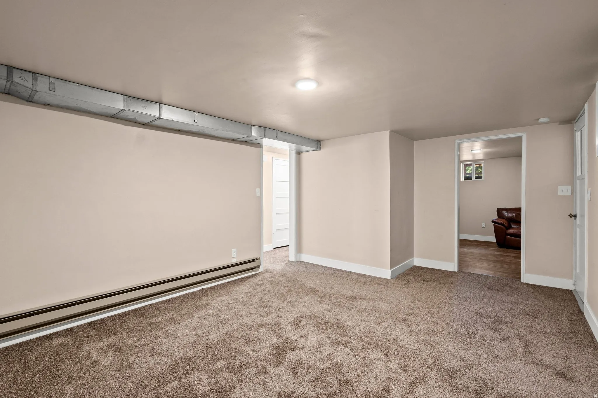 Carpeted spare room with a baseboard heating unit and baseboards