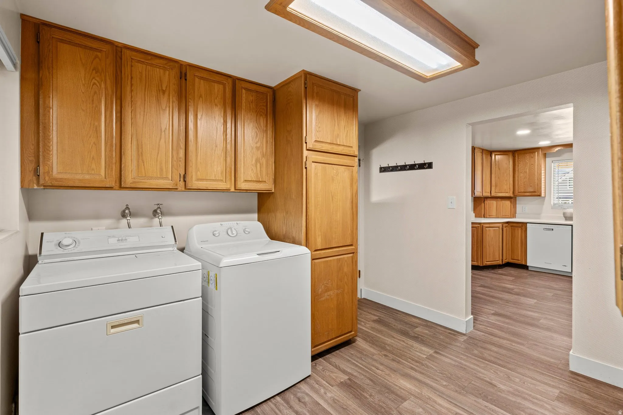 Laundry area with light wood-type flooring, independent washer and dryer, and cabinet space